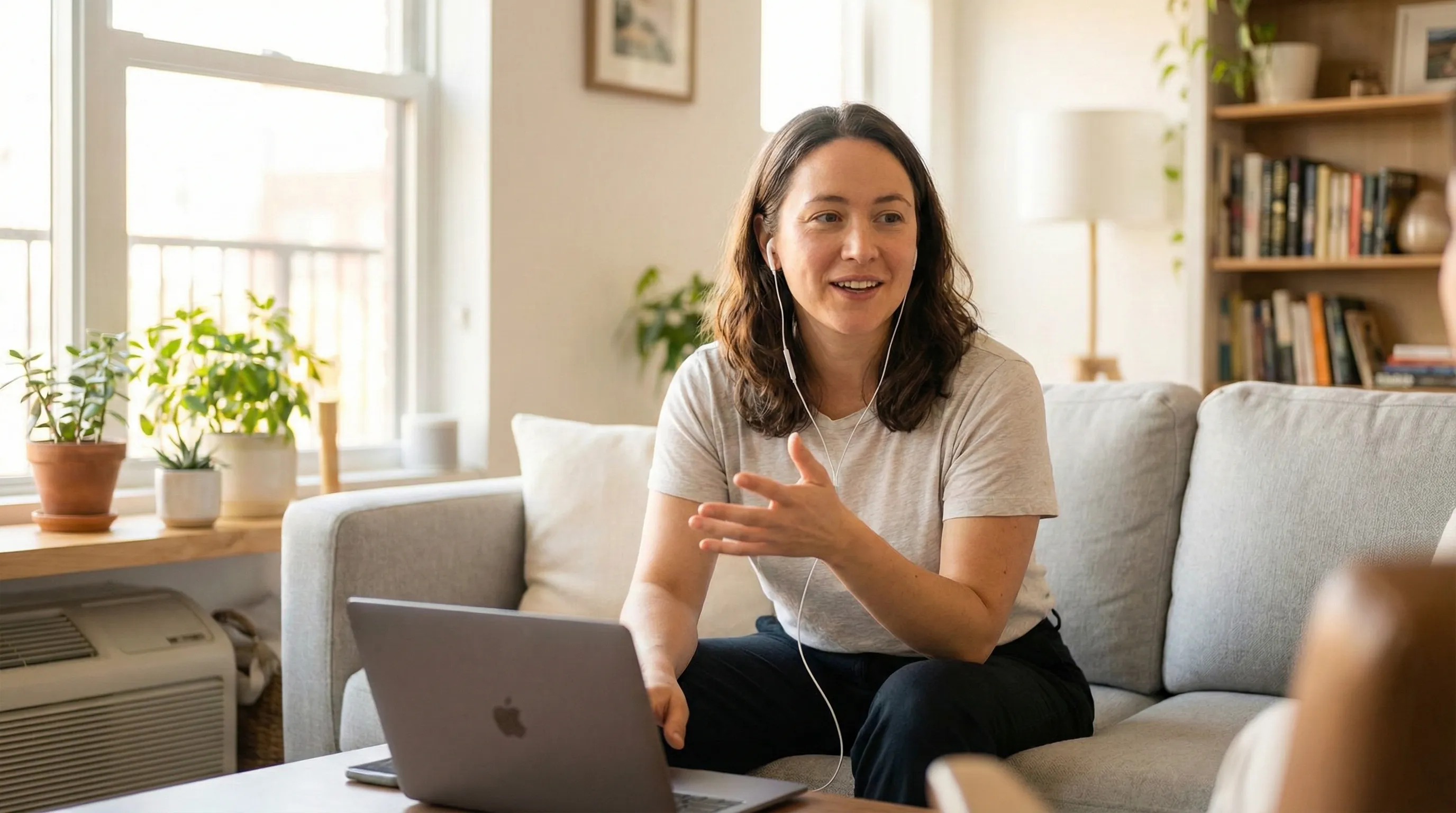 A person having a natural conversation with earbuds in, relaxed and engaged in a bright, airy space